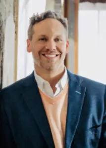 Kyle D. Venema, founder of Venergy Momentum, smiling in a professional headshot wearing a blue blazer and peach sweater.