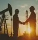 Silhouette of engineer and worker shaking hands in oil field.