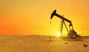 Oil pump jack in desert at sunset, highlighting economic potential and mineral rights value.