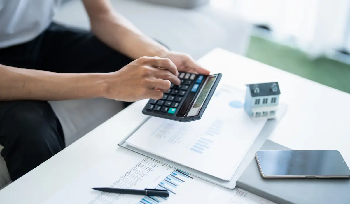 A mineral owner calculates potential taxes from selling oil royalties, using financial documents and a calculator. Represents the importance of a Retrospective Appraisal for accurate tax reporting.